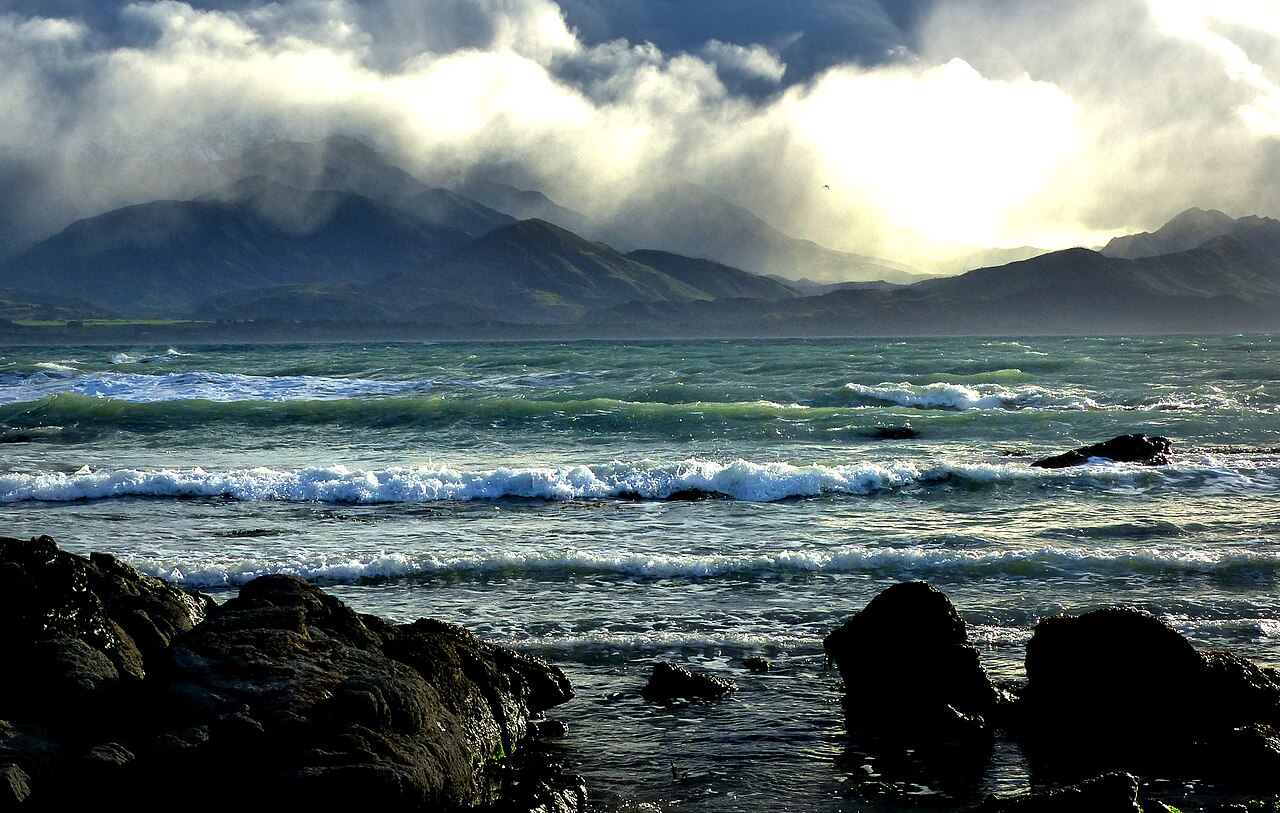 Regional view of the Kaikōura coast with foreground rocks, sea and mountains; not photographed at Mangamaunu.