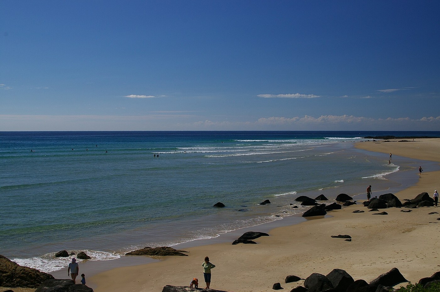 Rainbow Bay beach and Snapper Rocks in the distance, viewed from Greenmount with rocks in the foreground.