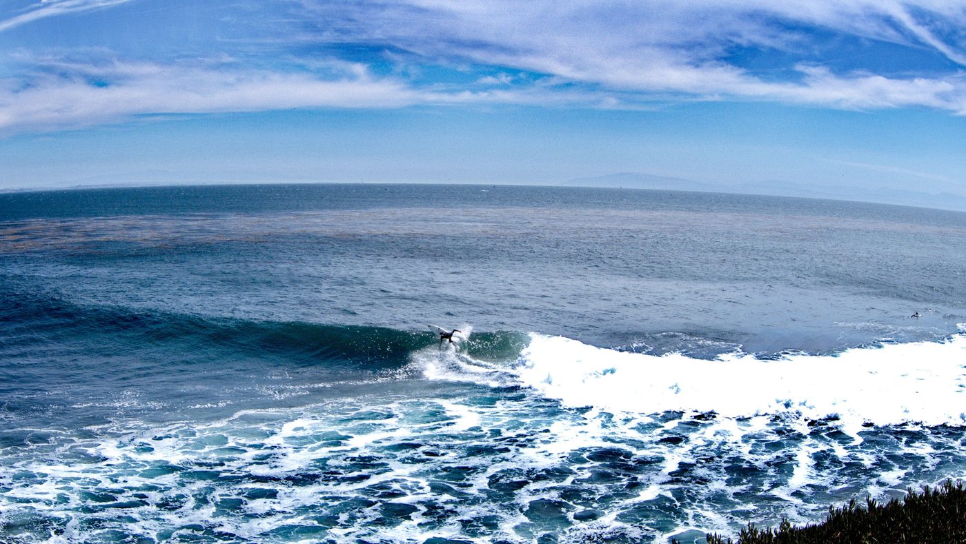 A surfer riding a wave at Steamer Lane in Santa Cruz, viewed from the shore.
